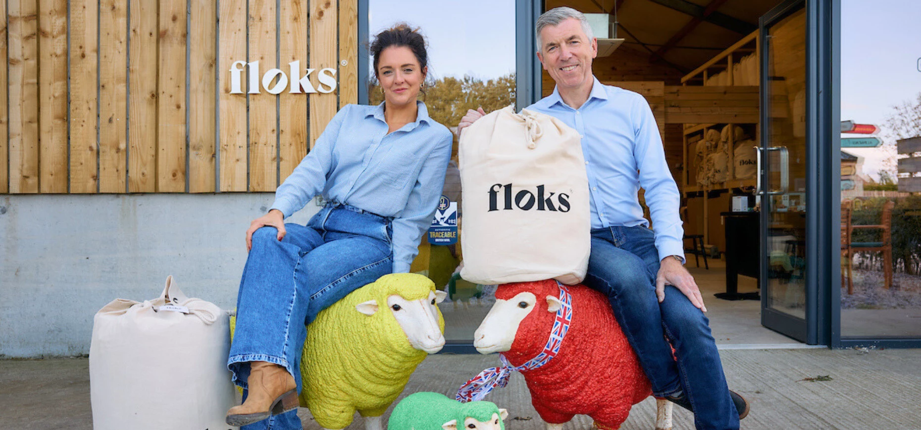 Floks founder Sophie Platts with David Wright of Mercia, sitting atop decorative sheep and holding sacks of wool.