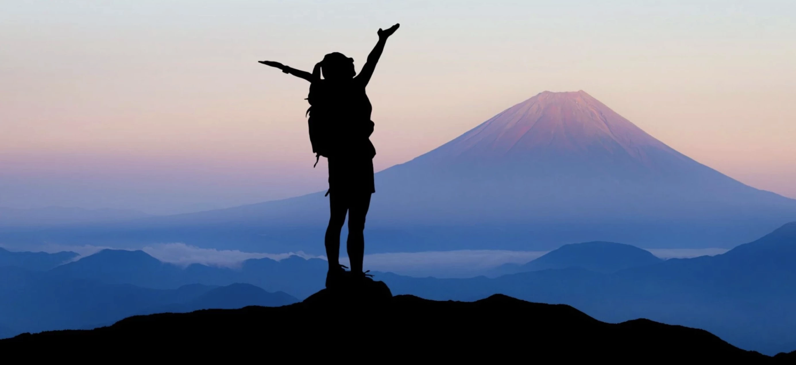 Figure stands triumphant at the top of a mountain