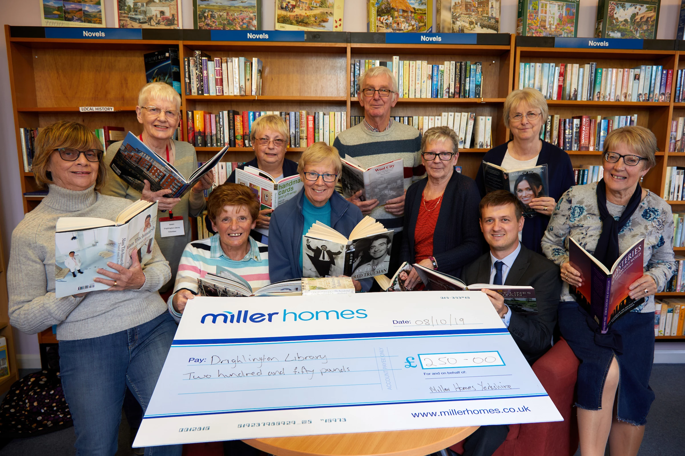 Chris Carlin of Miller Homes presents members of the Drighlington Library Volunteer group with their donation to be used to purchase new books.