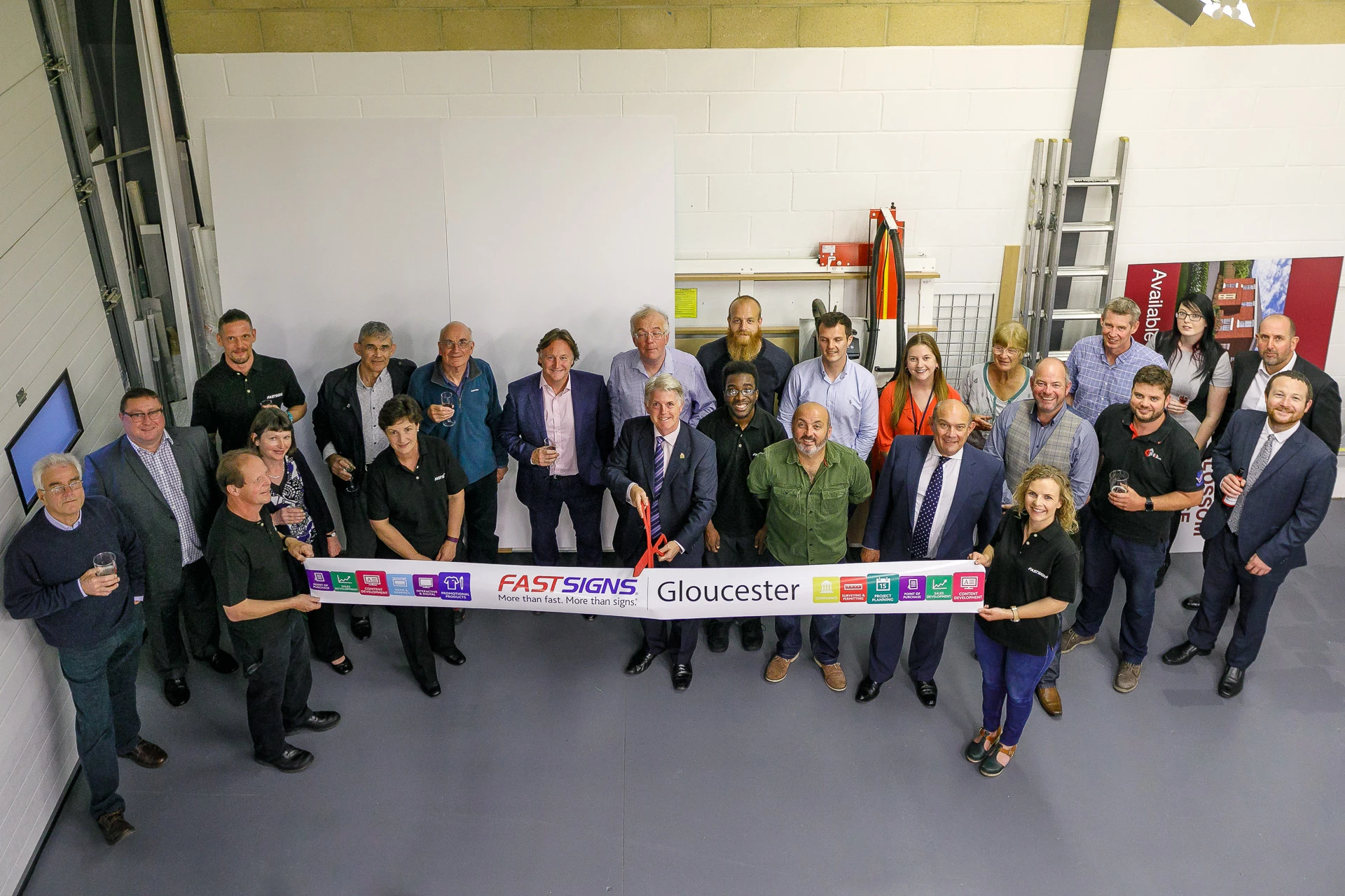 Councillor Paul James (centre) and the FASTSIGNS Gloucester team,  cutting the ribbon at the relocated centre. 