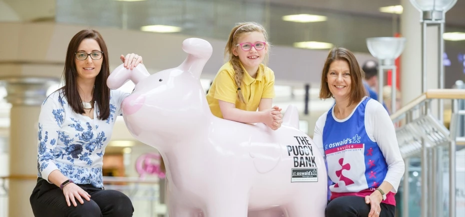 Raising funds with the Puggy Bank. (L-R) Clare Cannon, community manager intu north east, Hadrian School's Ellie-Marie Thompson (4), and Susan Jones, St Oswald's Hospice's head of corporate relationships; with the 'Puggy Bank' 