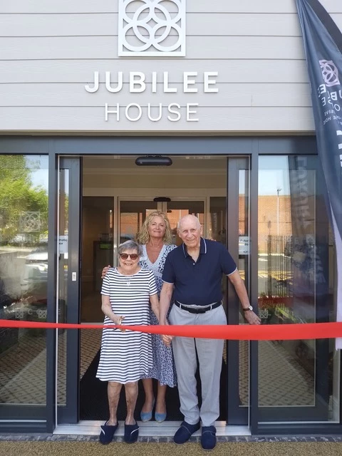 Care Home manager with two residents cutting a ribbon to open new home