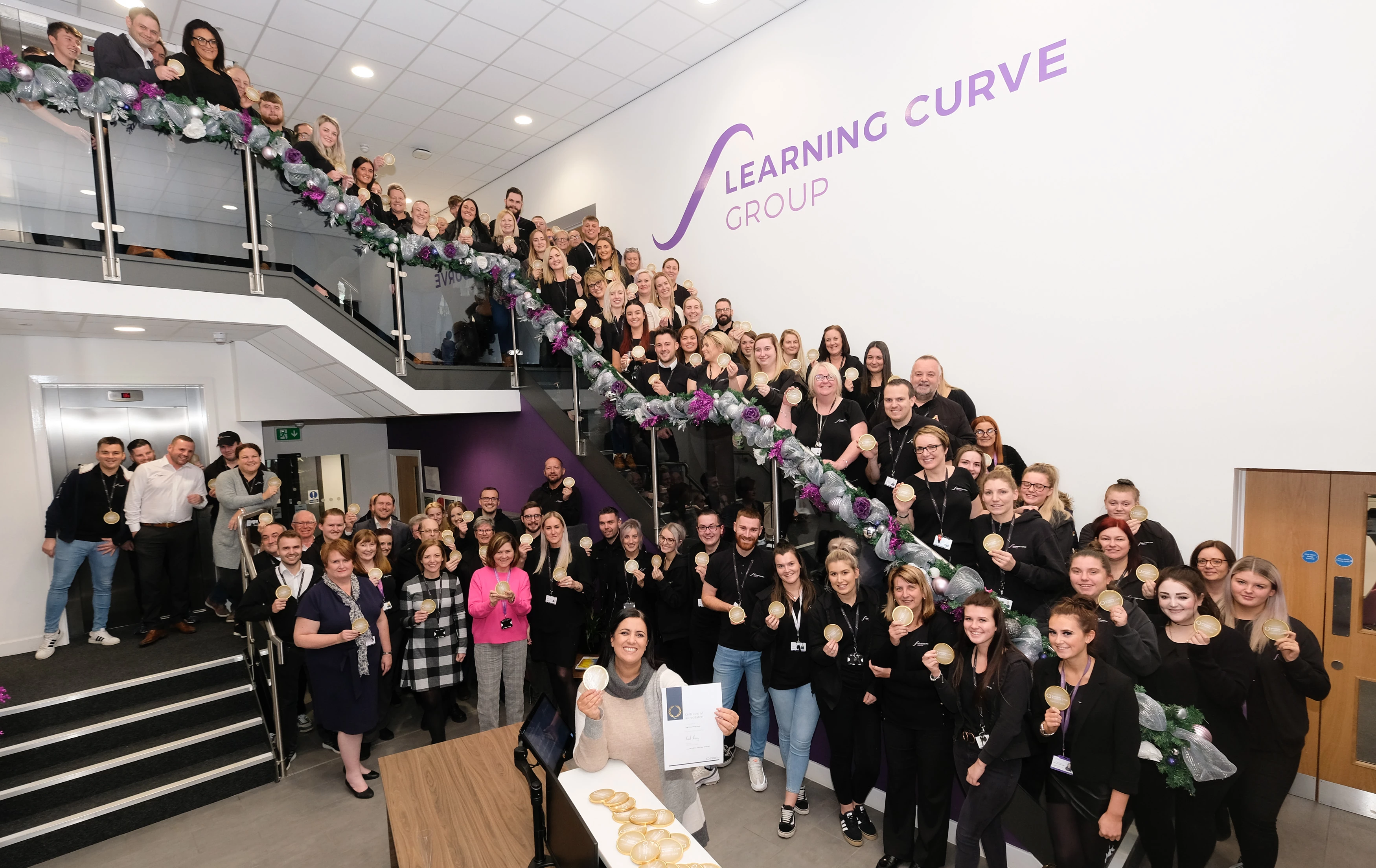 Learning Curve Group staff celebrating their IIP Gold award, with Brenda McLeish CEO