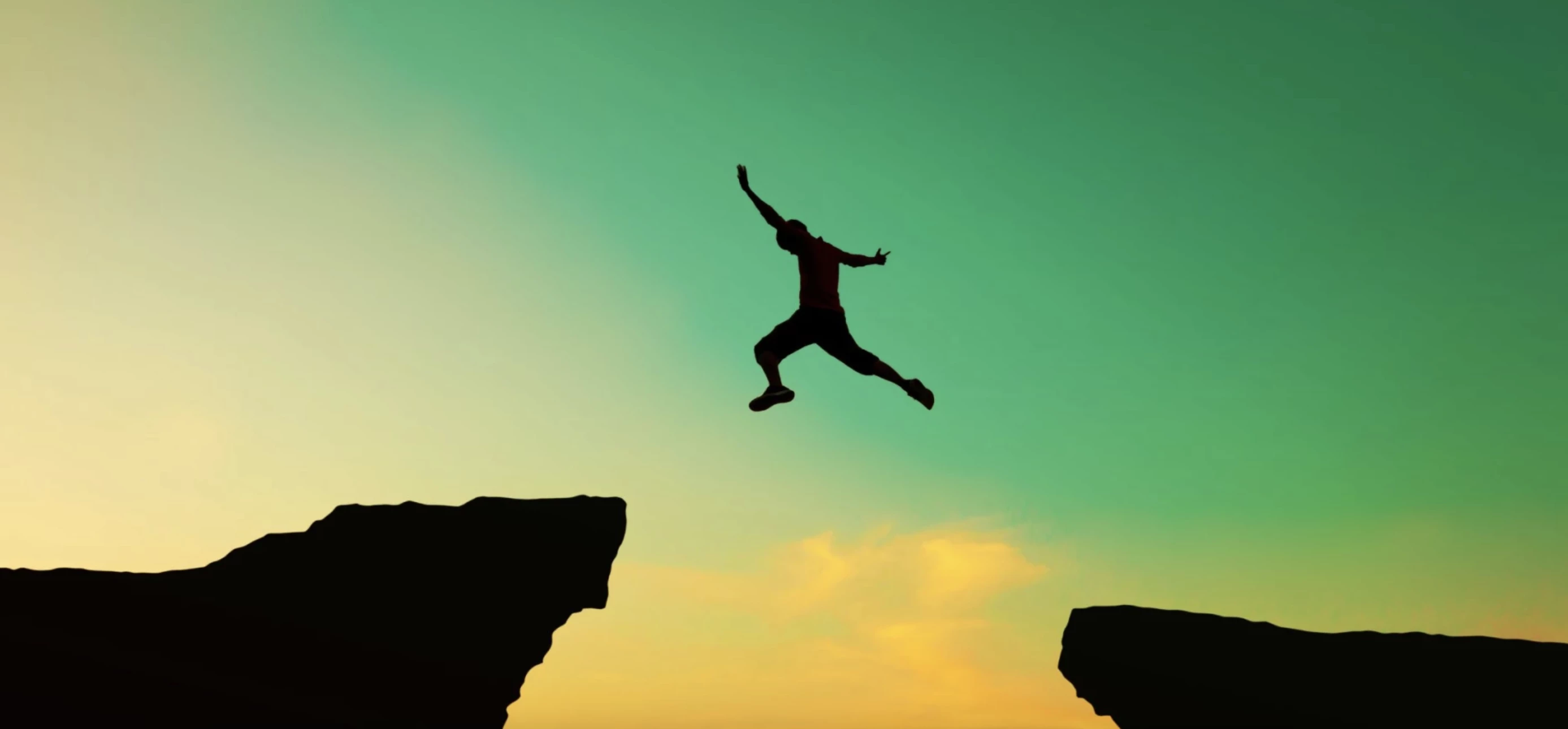 Blacked out figure jumping between two ledges in front of a green sky