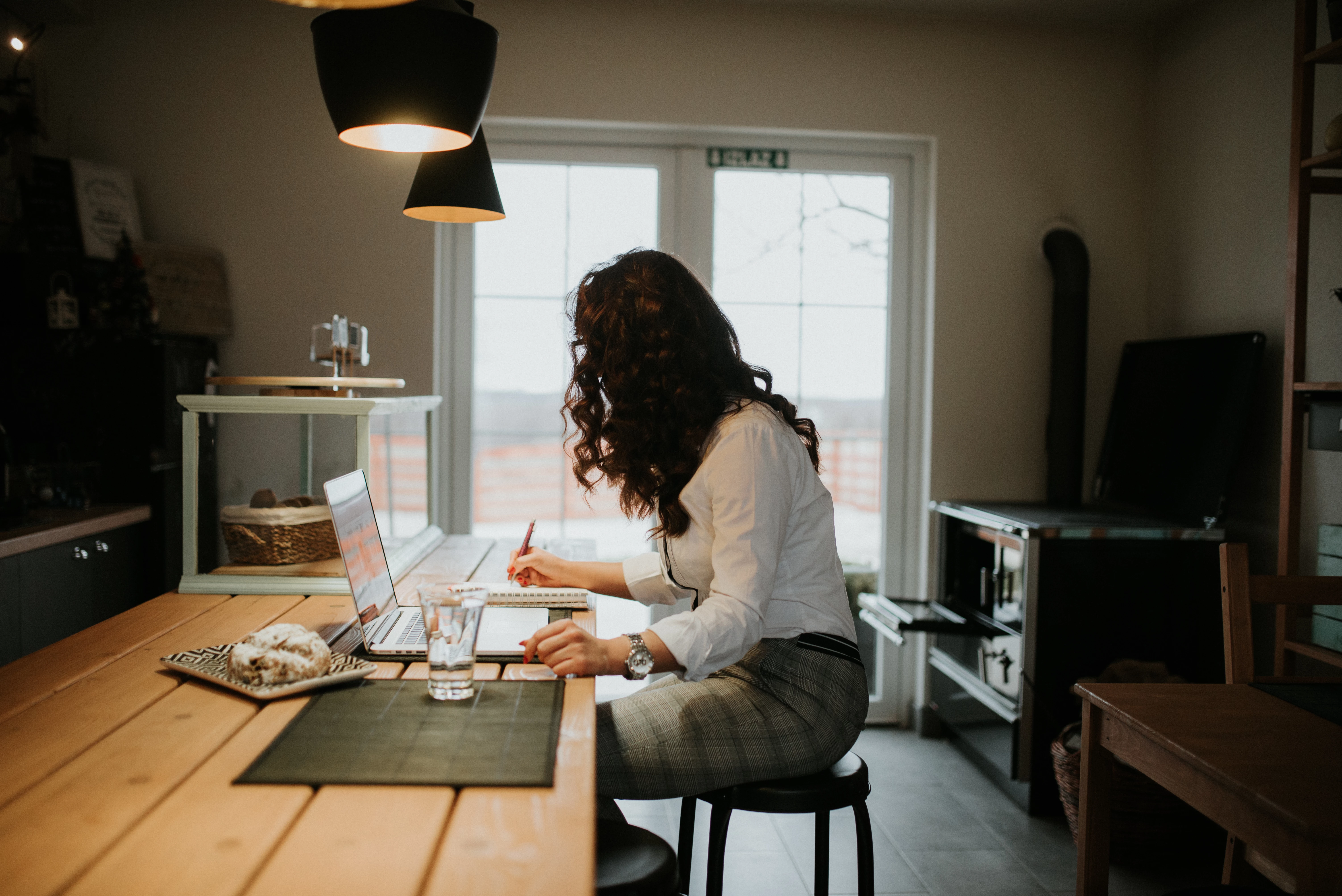 Young woman working on laptop and writing at home