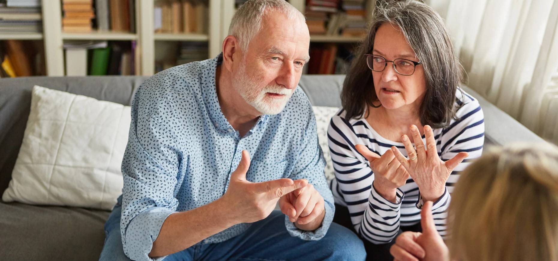 An older couple sitting on a sofa discussing their finances.