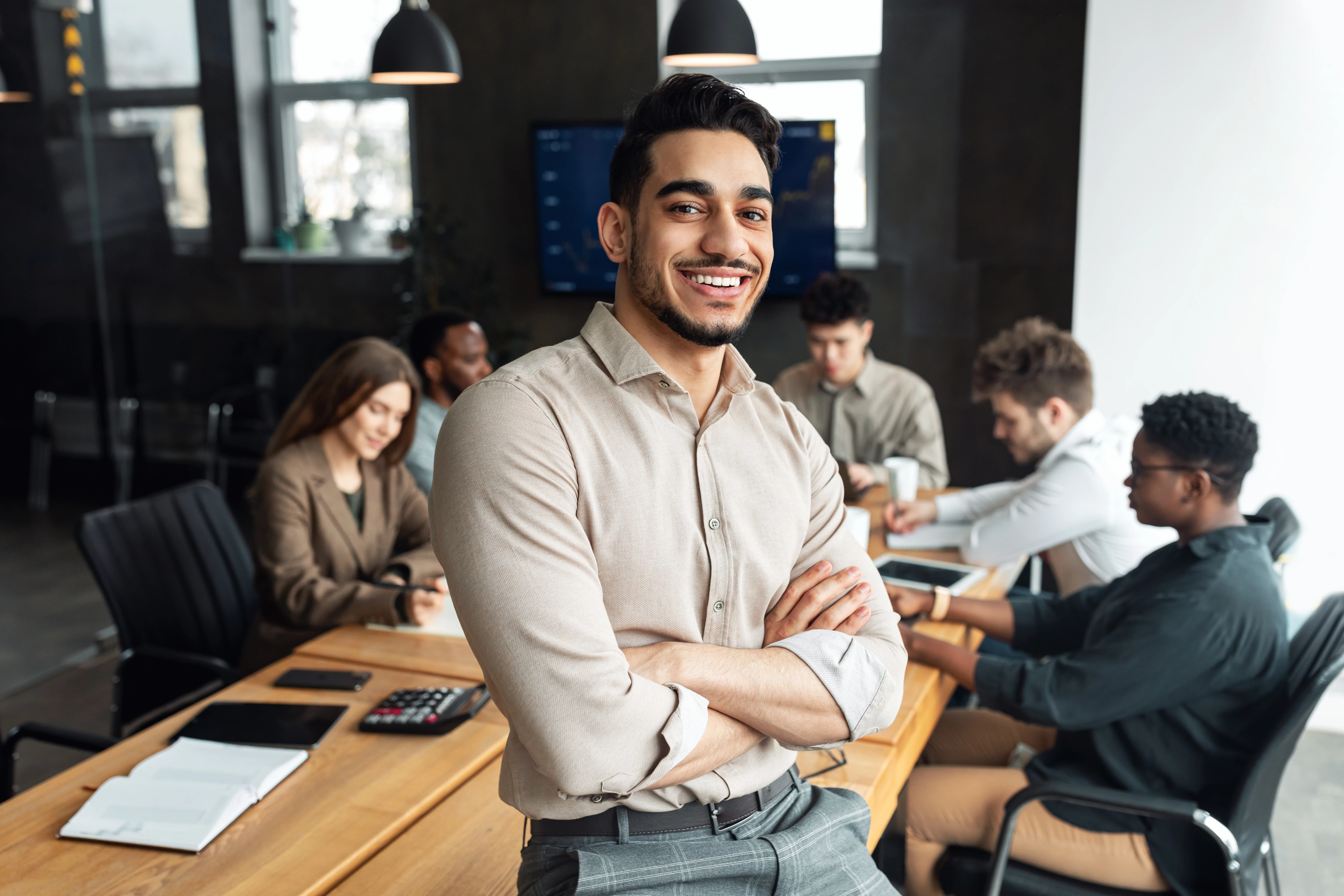 Young bearded businessman sitting on desk and posing - stock photo