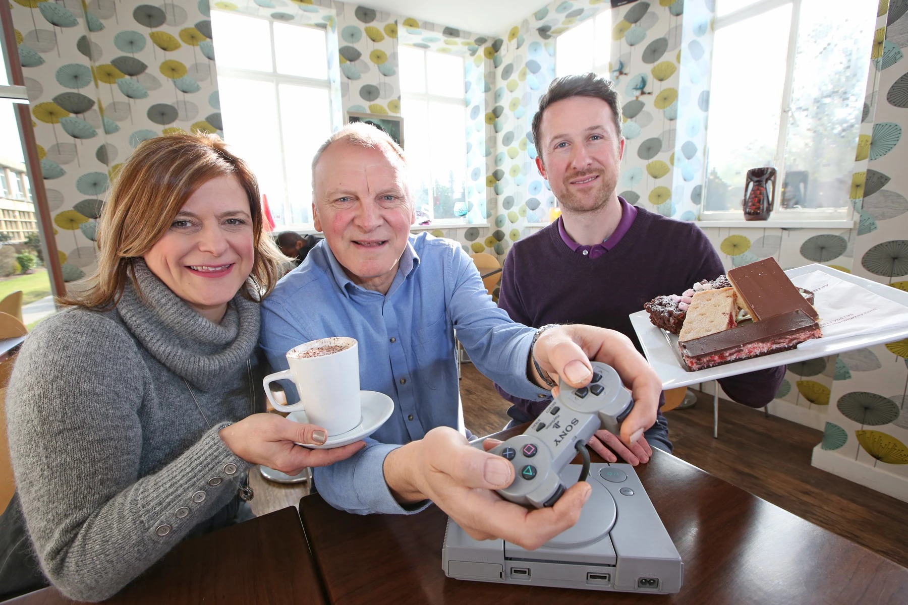 Eddie Humphries enjoys a go on the retro Playstation 1 game installed in the canteen watched by business owners Alex and Jeanette MacMurray.