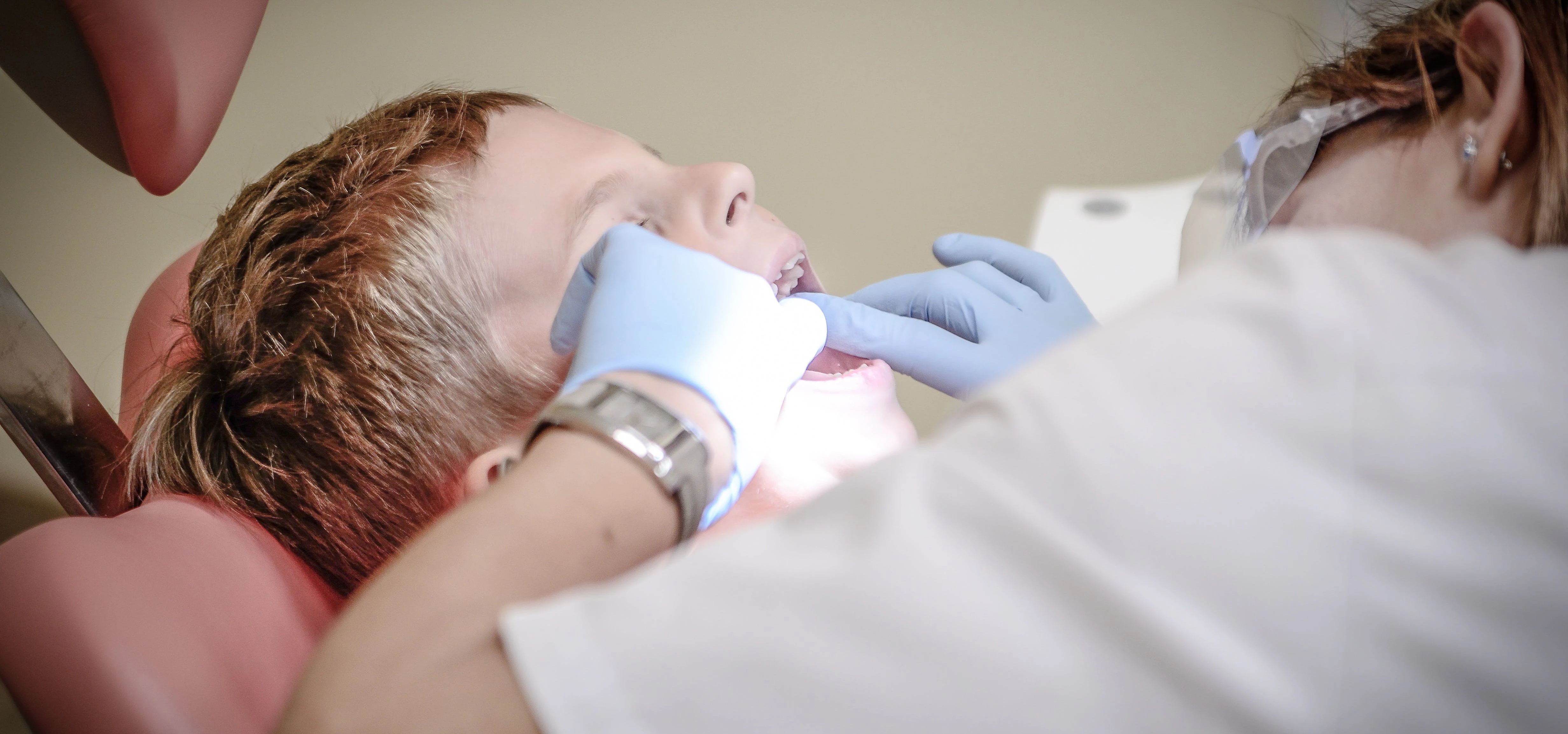 Dentist Woman Wearing White Gloves and White Scrubsuit Checking Boy's Teeth